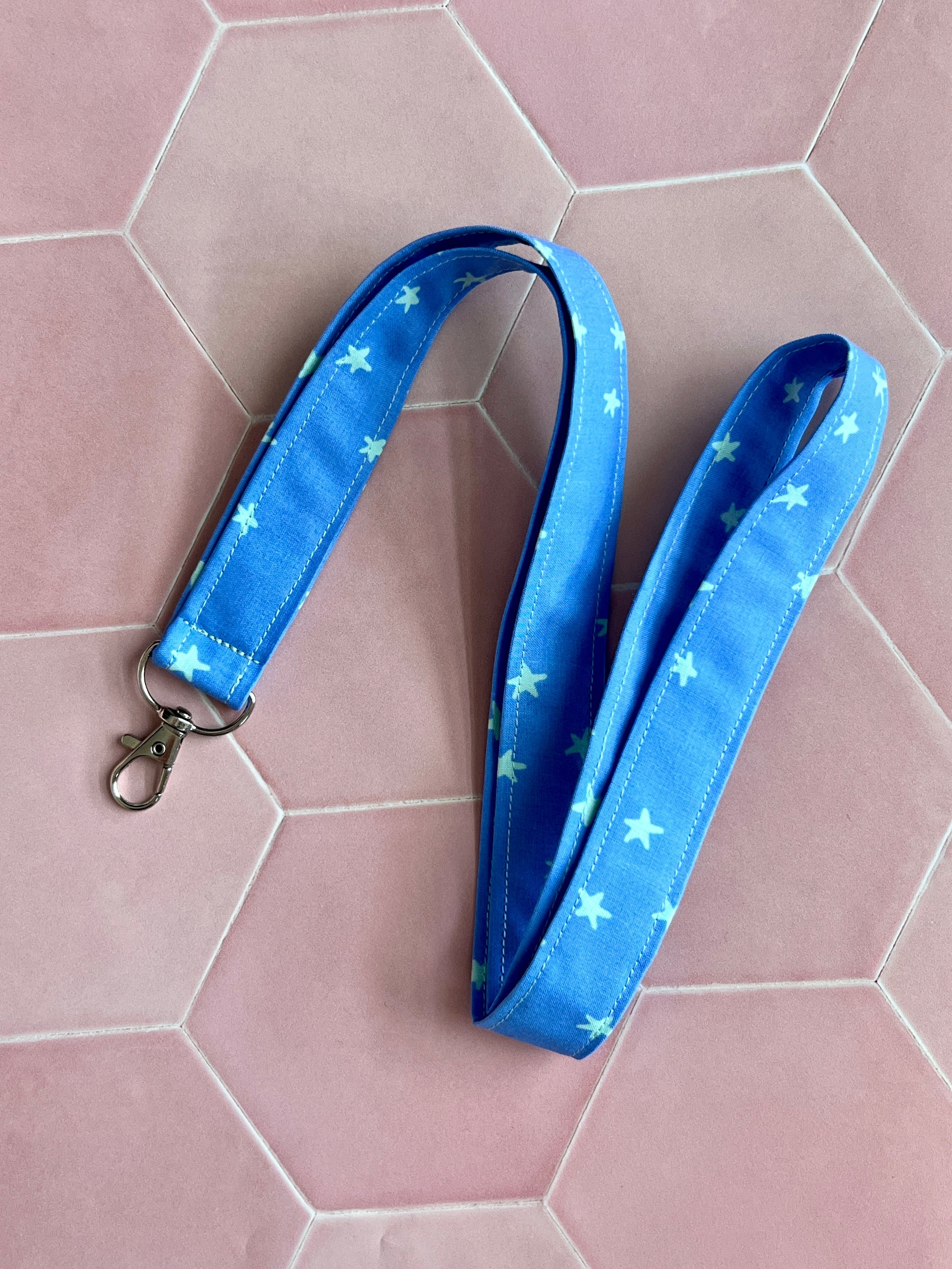 Flat lay of handmade fabric lanyard in blue with mint green stars, featuring metal D-ring, ideal for teachers and nurses.