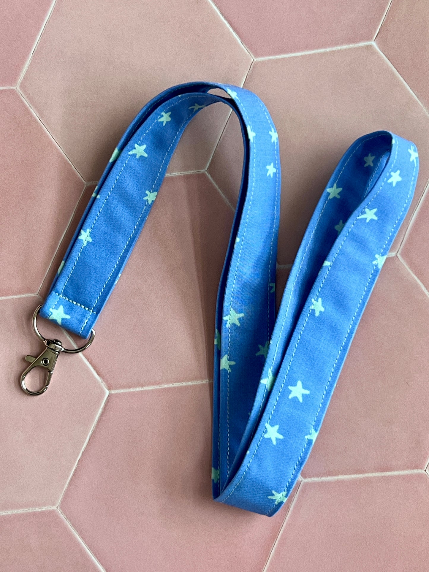Flat lay of handmade fabric lanyard in blue with mint green stars, featuring metal D-ring, ideal for teachers and nurses
