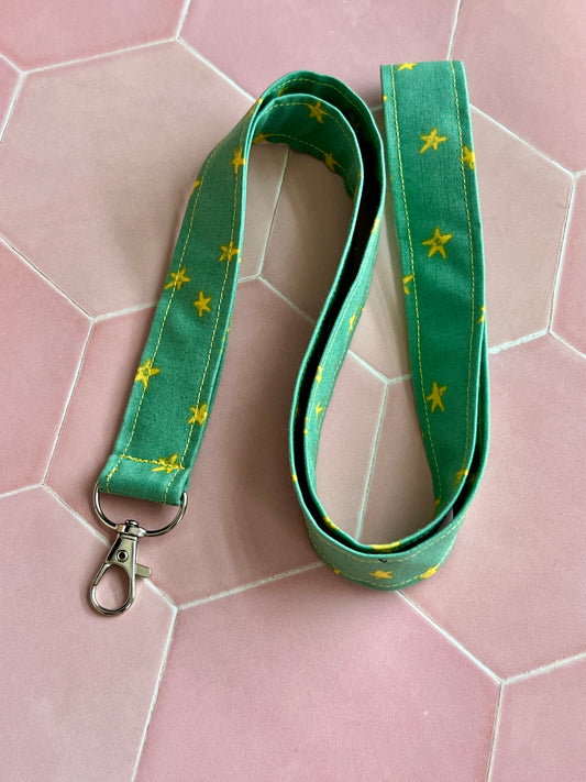 Green fabric lanyard with bright yellow stars, handmade with secure D-ring clasp for teachers, students, and professionals