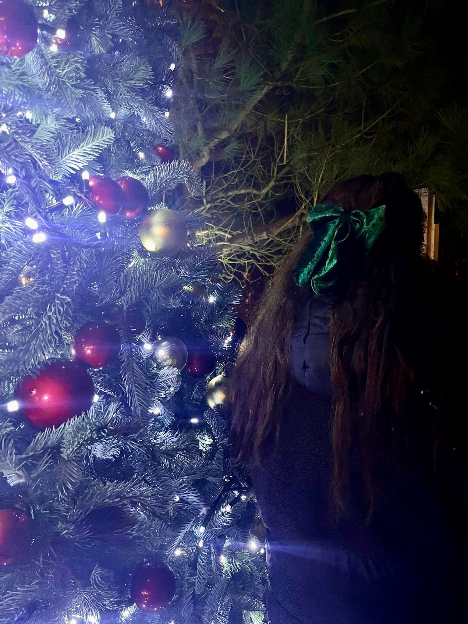 owner of sew much love standing next to christmas tree wearing green velvet hair bow 